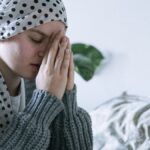 A woman wearing a scarf prays indoors, symbolizing hope and recovery from cancer.
