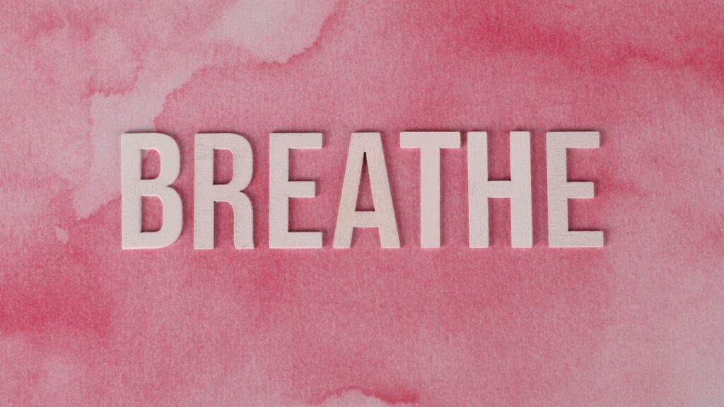 Motivational 'Breathe' text on a pink watercolor background, promoting relaxation and mindfulness.