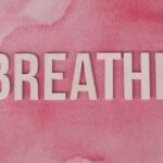 Motivational 'Breathe' text on a pink watercolor background, promoting relaxation and mindfulness.