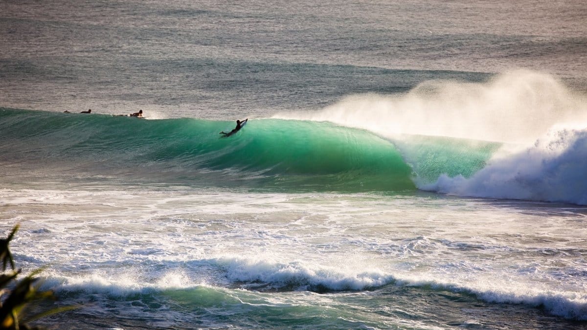 A surfer catches a wave at Burleigh Heads, Queensland, showcasing the beach's vibrant surfing scene.