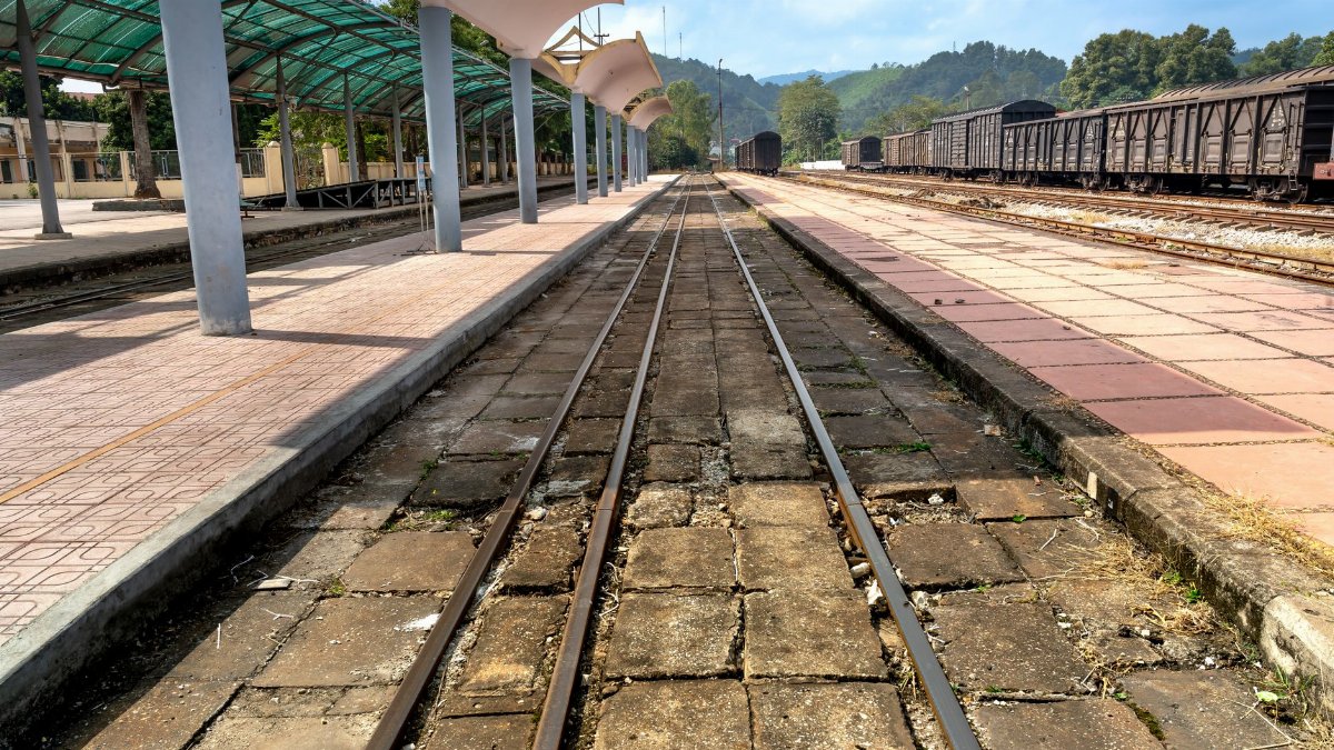 Deserted railway station platform with train tracks and hillside view, reflecting a serene travel moment.