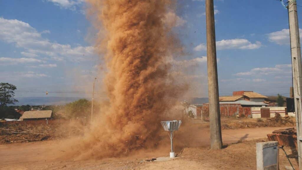 Impressive dust devil swirling on an open road in Tocantins, Brazil under a clear blue sky.