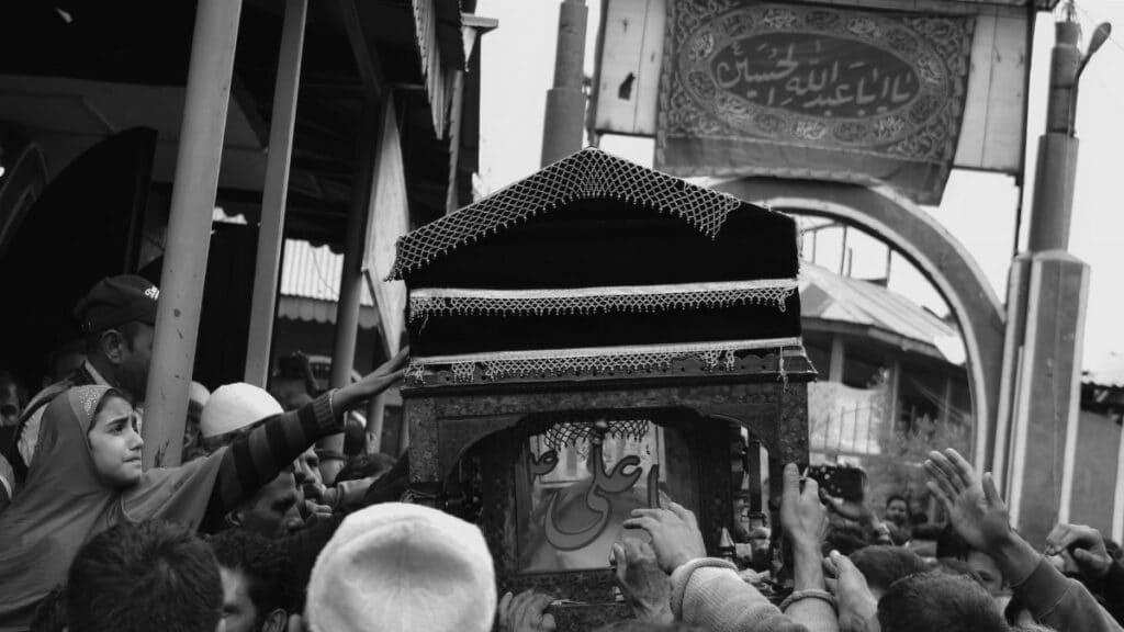 Crowd gathered for a traditional funeral procession in grayscale.