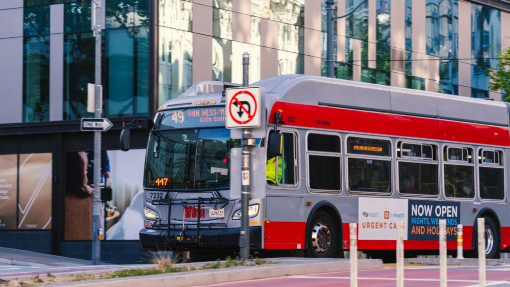 A San Francisco Muni bus traveling on Van Ness Avenue during the day in the cityscape.