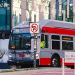 A San Francisco Muni bus traveling on Van Ness Avenue during the day in the cityscape.