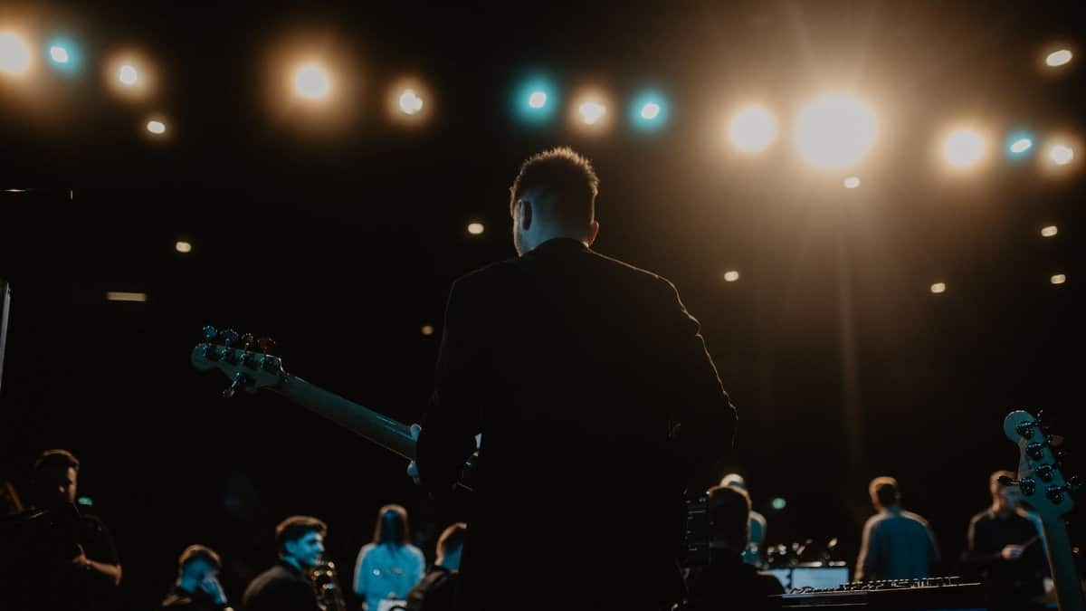 A captivating night concert scene featuring a guitarist and band on stage.