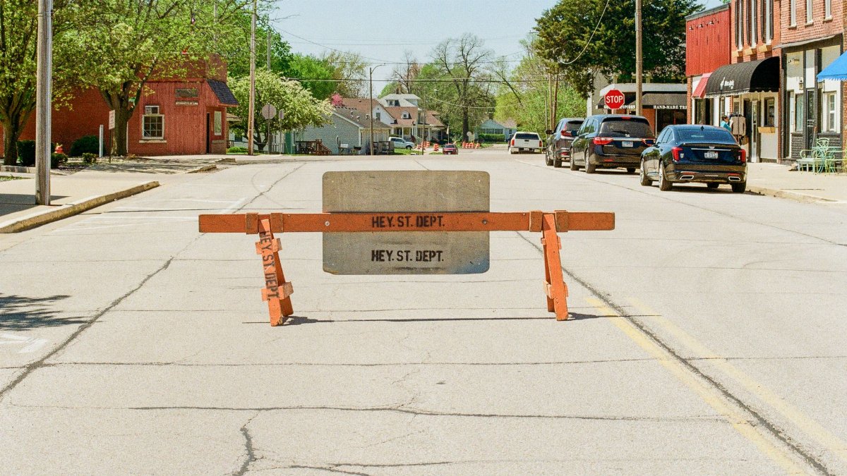 Empty city street with a barrier indicating closed road in a sunny neighborhood.