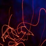 Vibrant neon light trails forming abstract patterns in a dark setting, creating a dynamic visual effect.