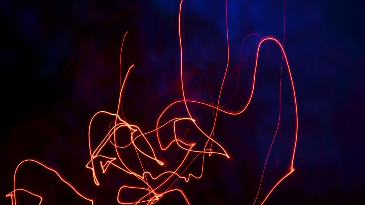 Vibrant neon light trails forming abstract patterns in a dark setting, creating a dynamic visual effect.
