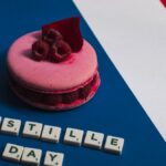 Pink macaron with raspberries on a French flag background, celebrating Bastille Day.
