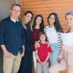 Smiling family with a realtor standing outside their new home, celebrating together.