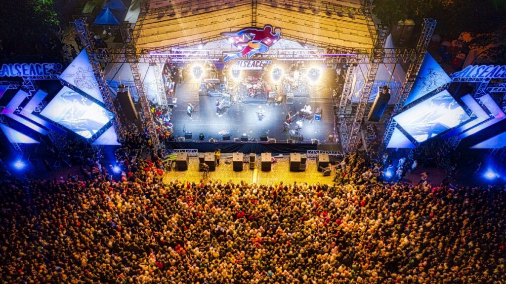 A lively aerial shot showcasing a large concert crowd at a bustling music festival.