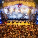 A lively aerial shot showcasing a large concert crowd at a bustling music festival.
