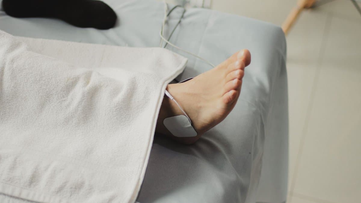A close-up image of a bare foot with a medical electrode, suggesting a healthcare setting.
