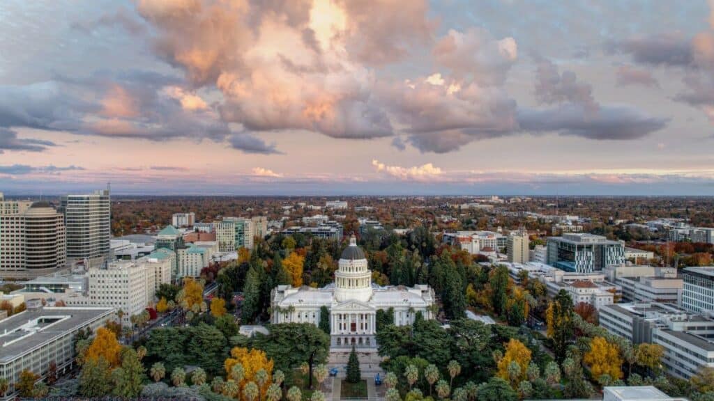 Stunning aerial view of the California State Capitol during a beautiful sunset with vibrant clouds.
