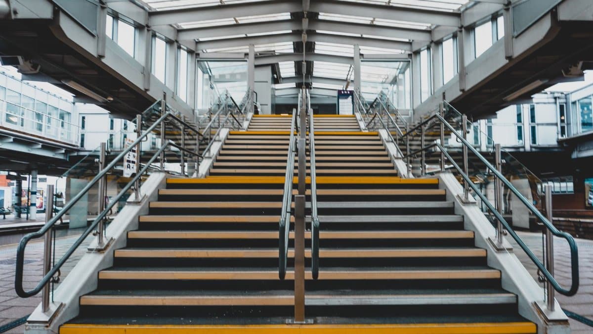Spacious indoor staircase with yellow-striped steps and steel handrails.
