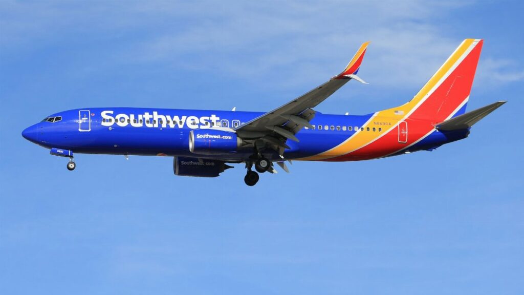 A vibrant Southwest Airlines airplane flying against a clear blue sky, showcasing its colorful livery.