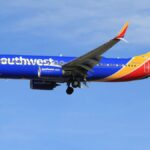 A vibrant Southwest Airlines airplane flying against a clear blue sky, showcasing its colorful livery.