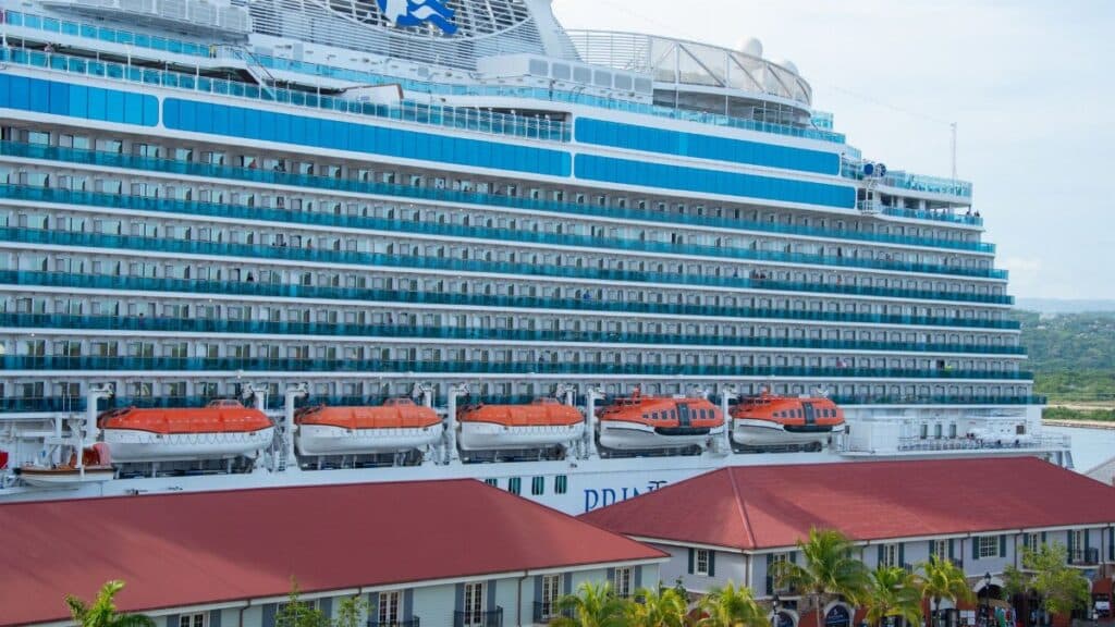 Large cruise ship Regal Princess docked at a vibrant harbor with visible lifeboats and luxurious amenities.