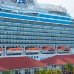 Large cruise ship Regal Princess docked at a vibrant harbor with visible lifeboats and luxurious amenities.