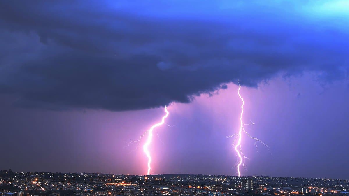 Vivid lightning strikes illuminating a nighttime Johannesburg cityscape beneath dark, ominous clouds.
