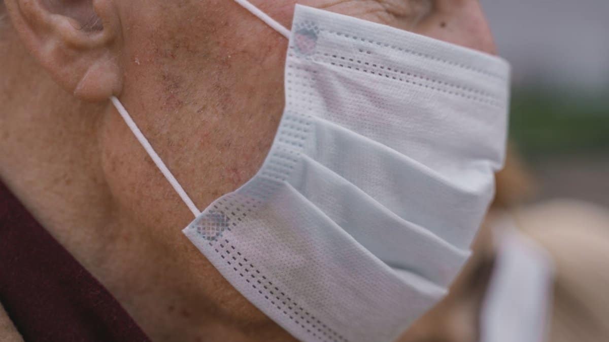 Detailed shot of an elderly man wearing a protective face mask, highlighting facial details and mask texture.