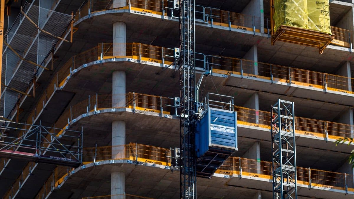Detailed view of a high-rise building construction featuring a crane and multi-level scaffolding.