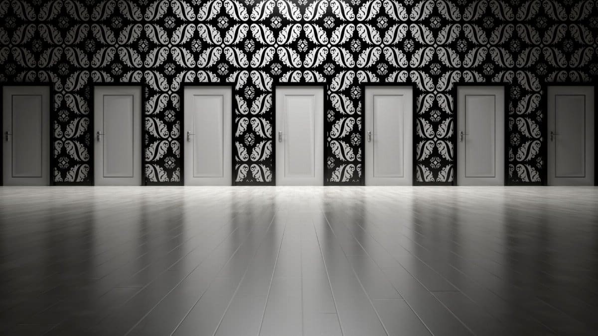 Five closed doors in a black and white ornate hallway symbolizing opportunities and decisions.