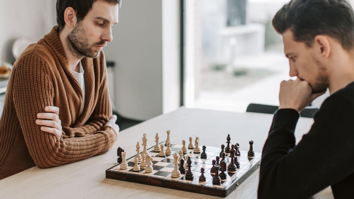 Two men focus intently on a chess match at home, creating a strategic atmosphere.