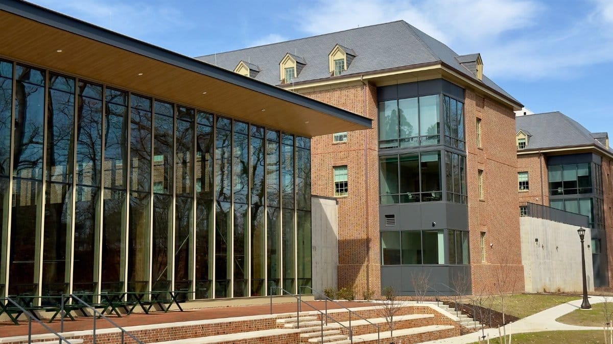 Exterior view of a modern academic building featuring large glass windows and brick architecture on a sunny day.