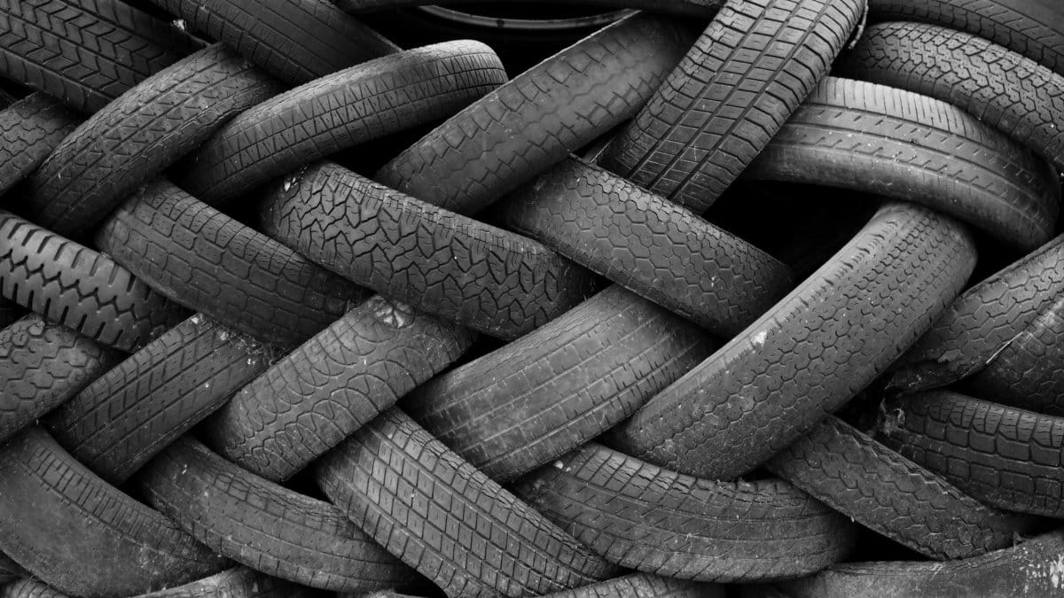 A black and white image showcasing a pile of old rubber tires intricately stacked, creating a textured pattern.
