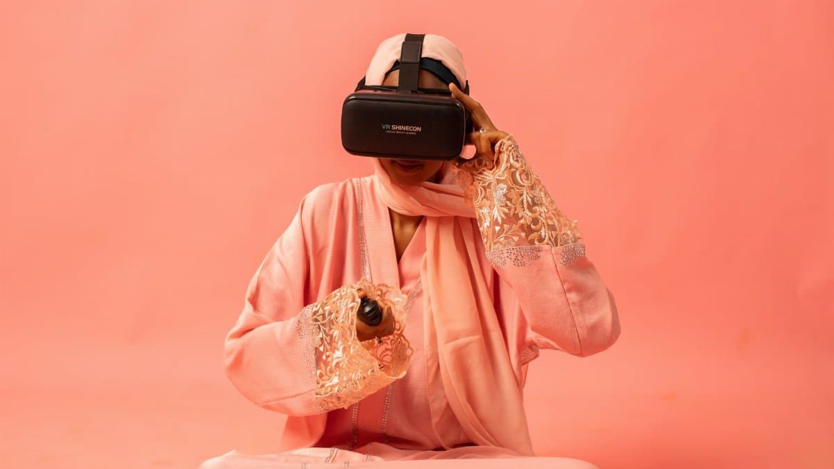 Woman in pink traditional clothing using a VR headset against a pink backdrop.