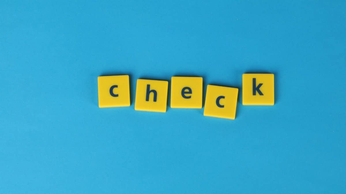 Yellow letter tiles spelling 'check' on a vibrant blue background, conveying approval or verification.