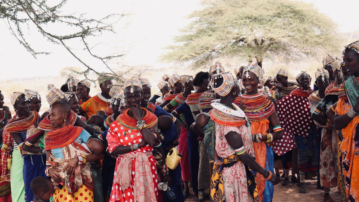 Vibrant gathering of African women in traditional attire celebrating outdoors.