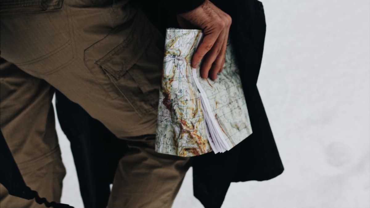 Close-up of a person holding a map against a snowy backdrop, suggesting outdoor exploration.