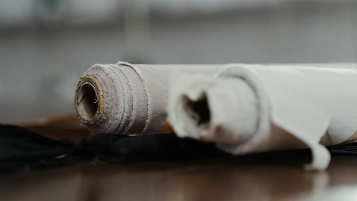 Rolled fabrics on a workshop table, highlighting textures and materials in a sewing environment.