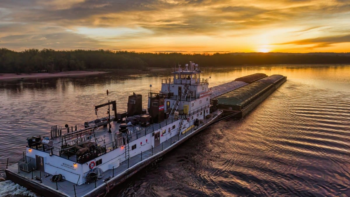 A picturesque towboat pushing barges on the Mississippi River at sunset in Reads Landing, Minnesota.