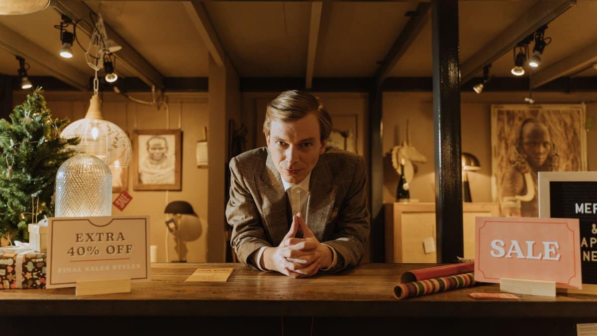 Salesman in a shop offering discounts and sales promotions with 40% off signs.
