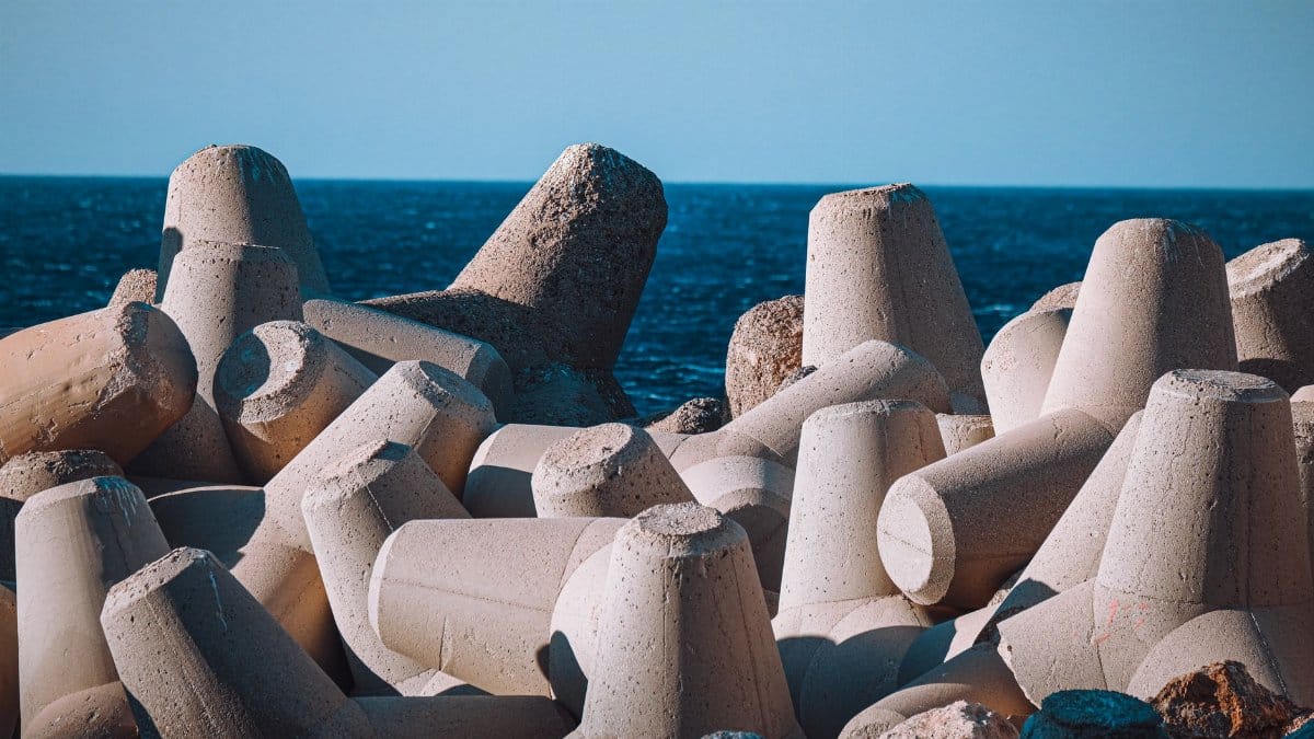 Concrete tetrapods form a solid breakwater against the blue sea under a clear sky.