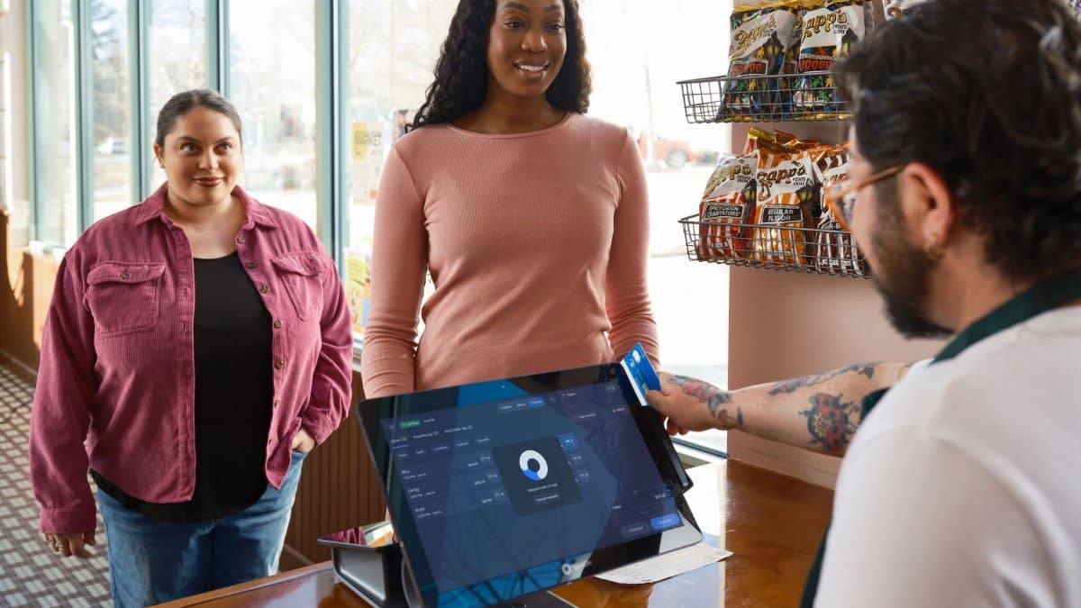 Two women making a payment at a convenience store using a touch screen POS system.
