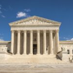 The majestic facade of the United States Supreme Court under a clear blue sky.
