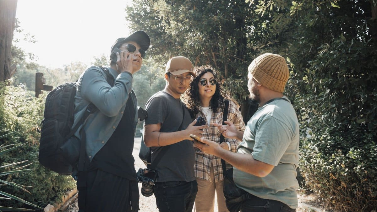 Four friends engage in a lively conversation during a nature walk under the bright sun.