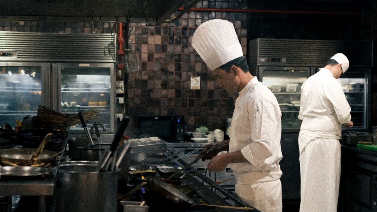 Two chefs in a professional kitchen preparing meals with focus and precision.