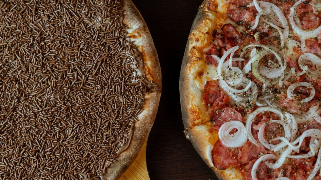 Close-up of chocolate and savory pizza halves on a wooden surface.