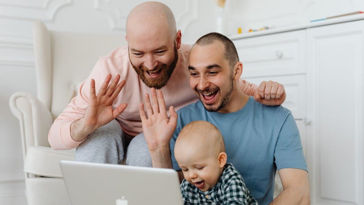 Loving same-sex couple with baby on a video call. Warm family moment.