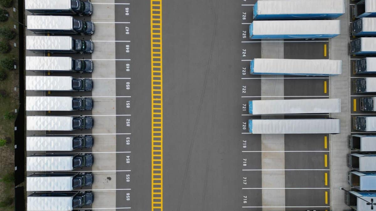 Top-down view of lined-up trucks at a logistics parking lot, showing organized transportation hub.