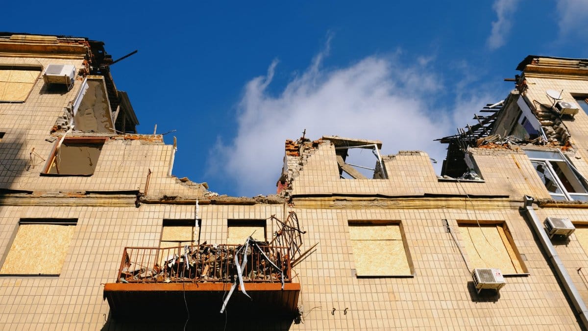 A destroyed residential building in Kharkiv, Ukraine under a blue sky.
