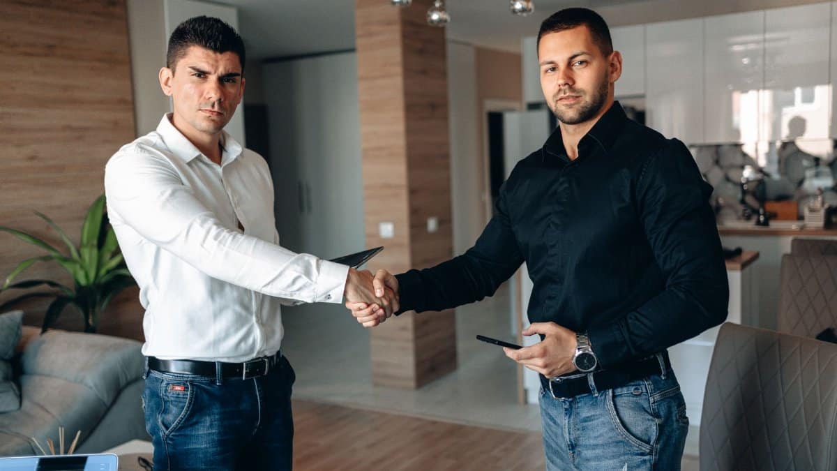 Two businessmen shaking hands in a modern office, symbolizing a successful business deal.