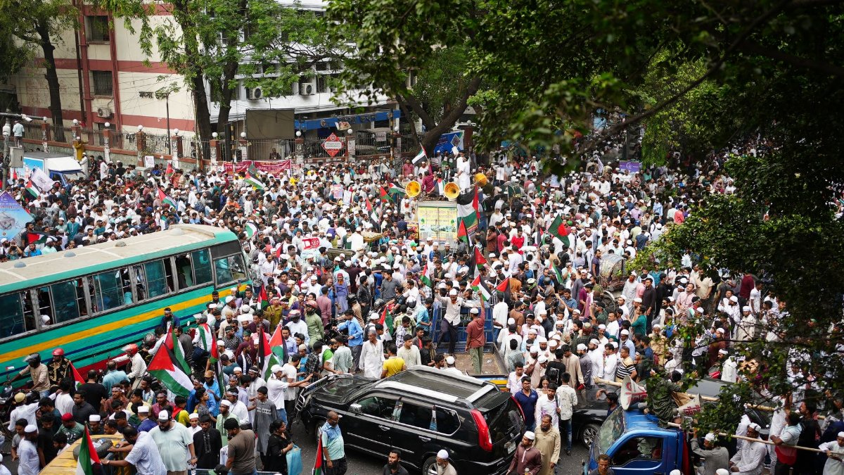 A large crowd of protestors gathering with flags in Dhaka, Bangladesh.