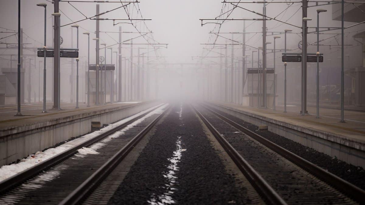 Misty railway platform enveloped in fog at a winter station.